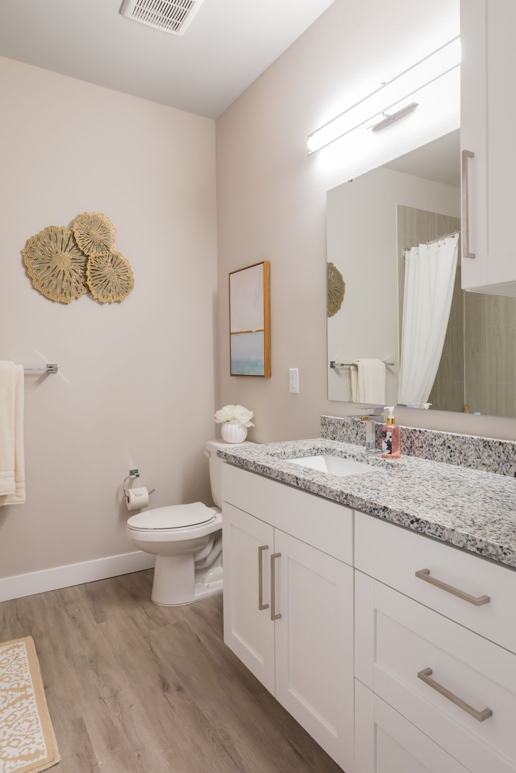 A bathroom with a toilet , sink and mirror.
