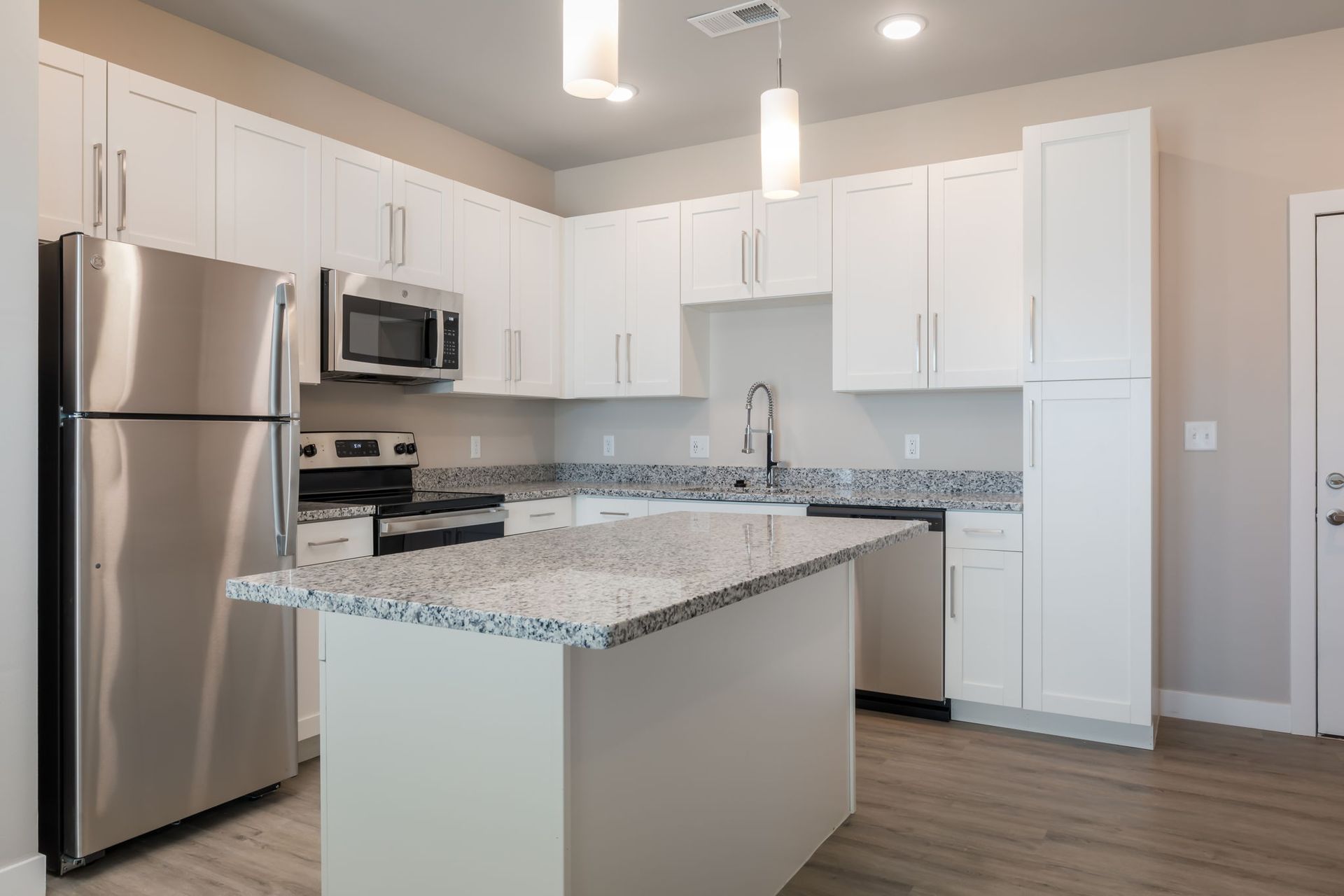 A kitchen with white cabinets , stainless steel appliances , and a large island.