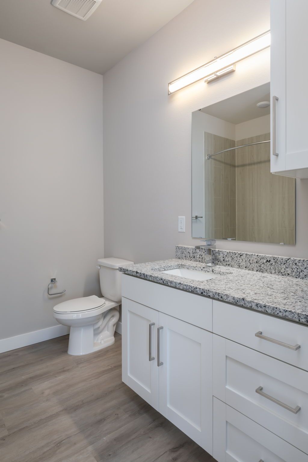 A bathroom with a toilet , sink , and mirror.
