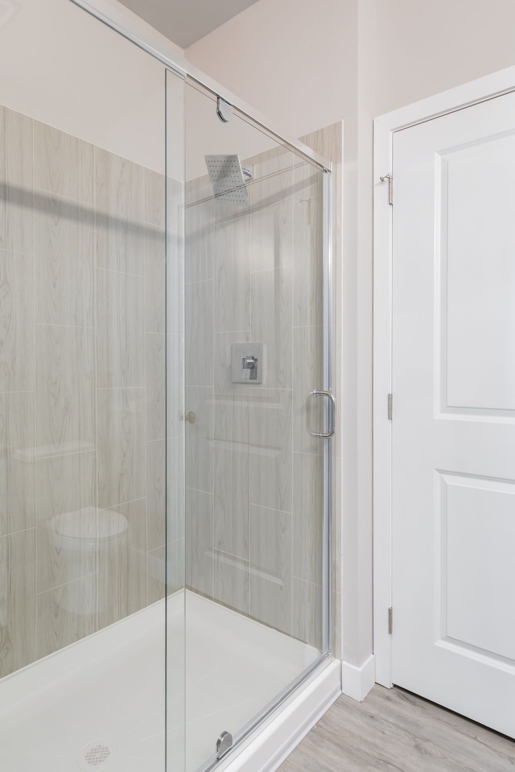 A bathroom with a walk in shower with a glass door.