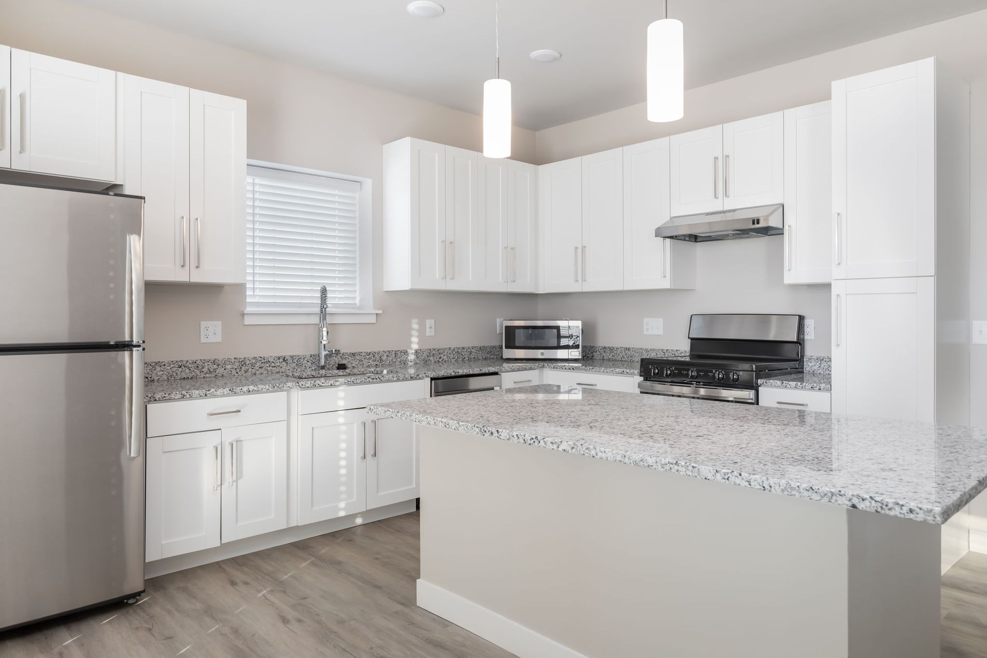 A kitchen with white cabinets , stainless steel appliances and granite counter tops.