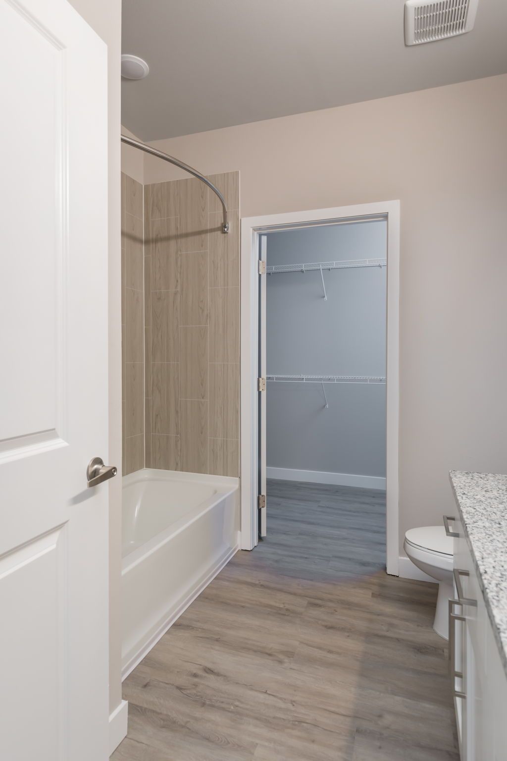 A bathroom with a tub , sink , toilet and walk in closet.