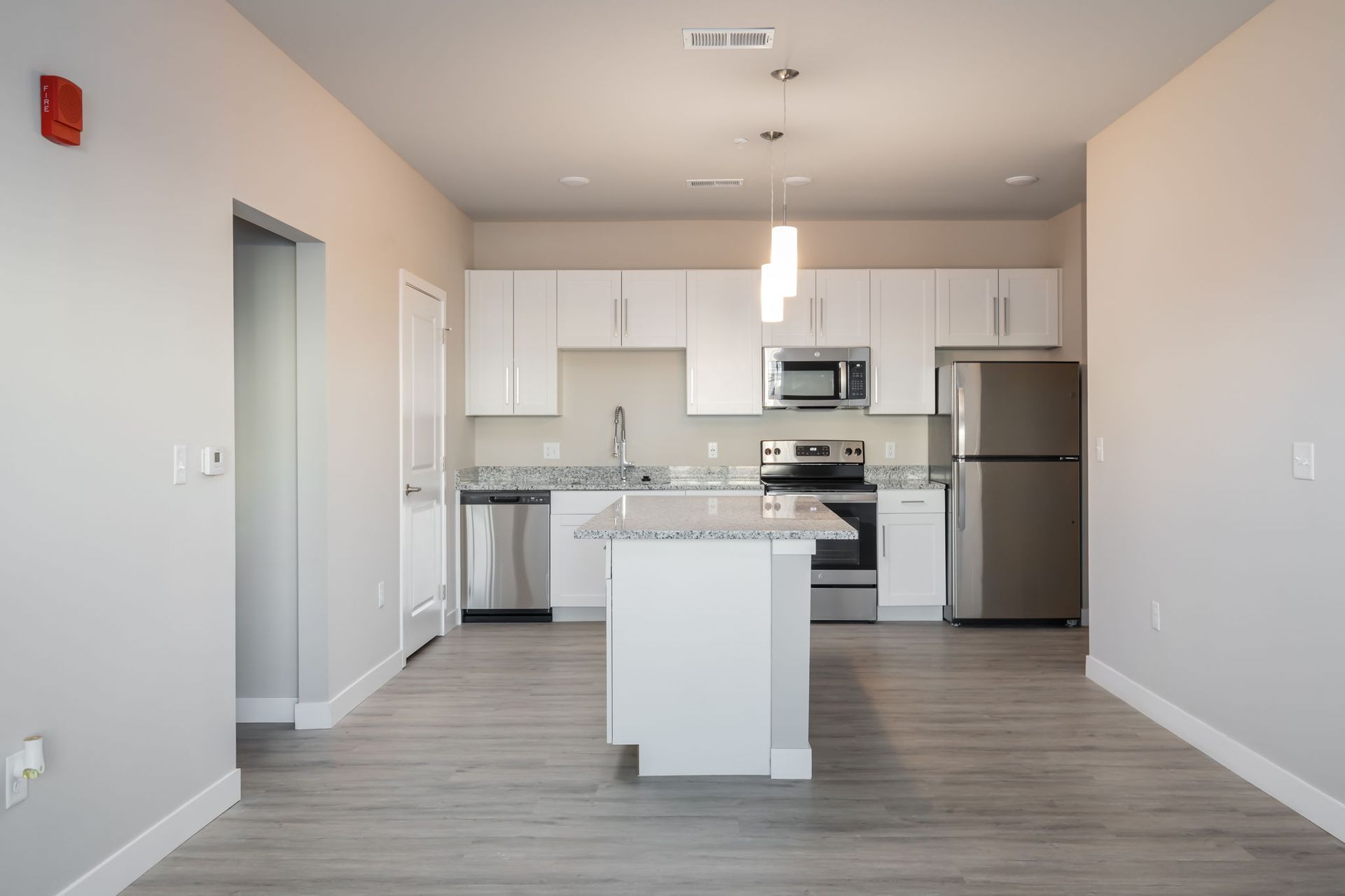 An empty kitchen with white cabinets and stainless steel appliances.