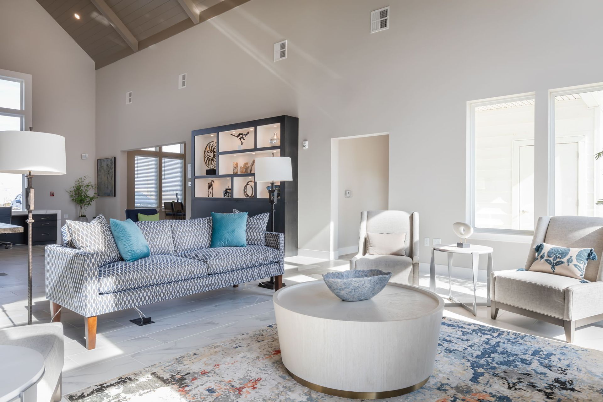 A living room with a couch , chairs , and a round coffee table.