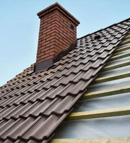 Brown tiled roof with a brick chimney and exposed underlayment on the right side