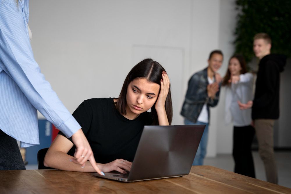 workplace investigations image of a man in a suit is pointing at a woman sitting at a desk .