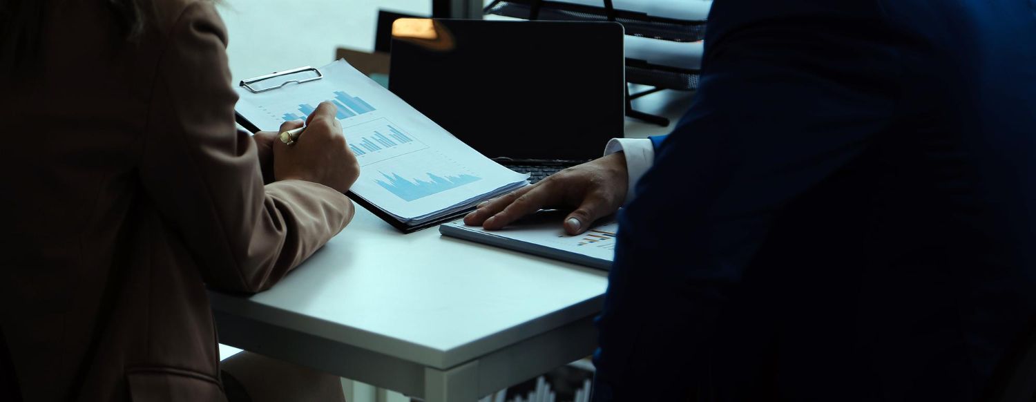 workplace investigations image of a group of people are sitting at a table using laptops and calculators .