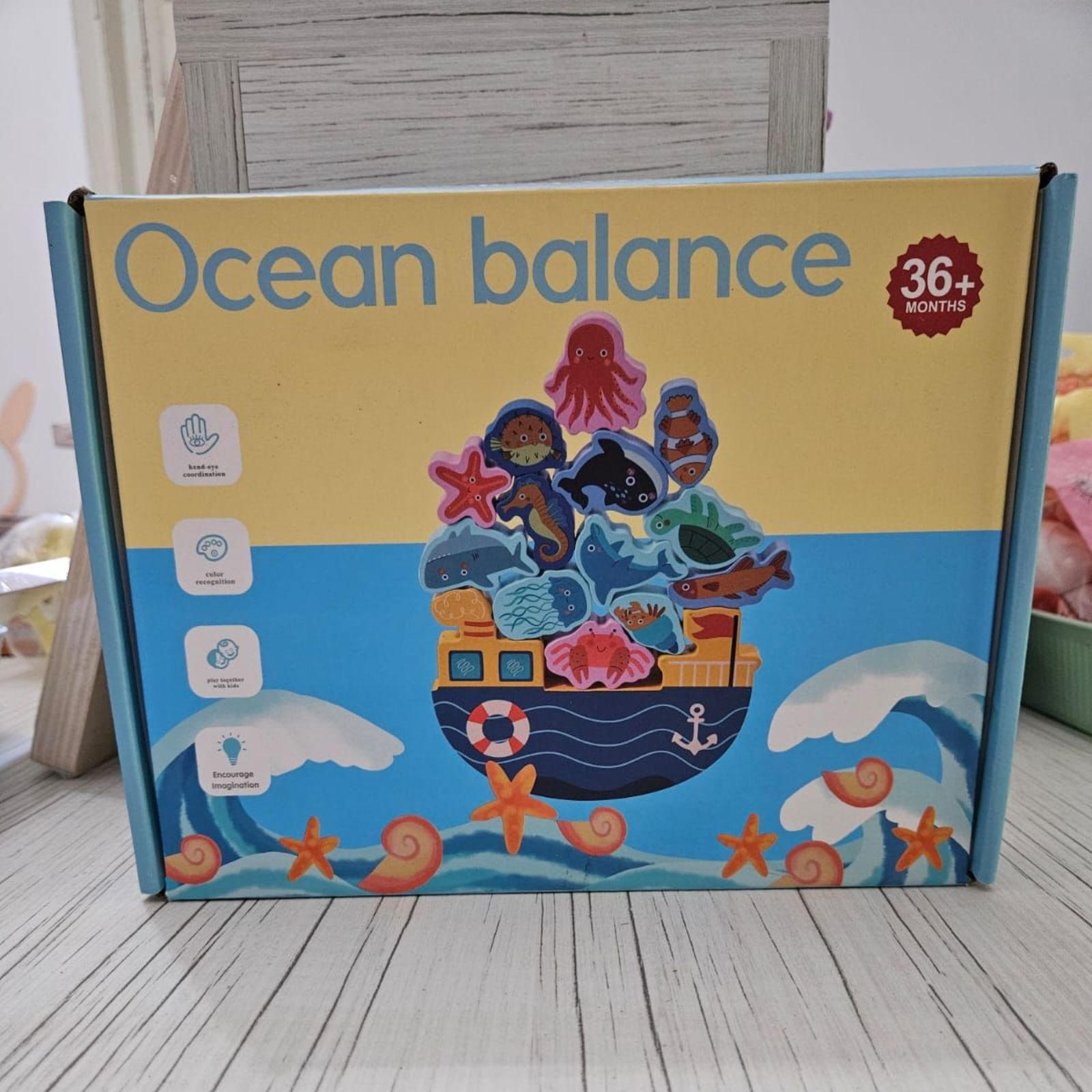 Caja para juego de equilibrio oceánico con criaturas marinas encima de un barco sobre olas azules.