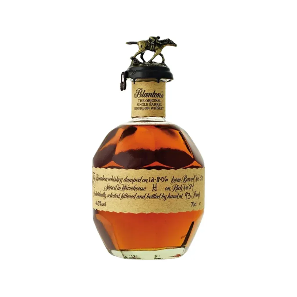 Bottle of Blanton's bourbon with a gold horse and jockey stopper, amber liquid, and a beige label.
