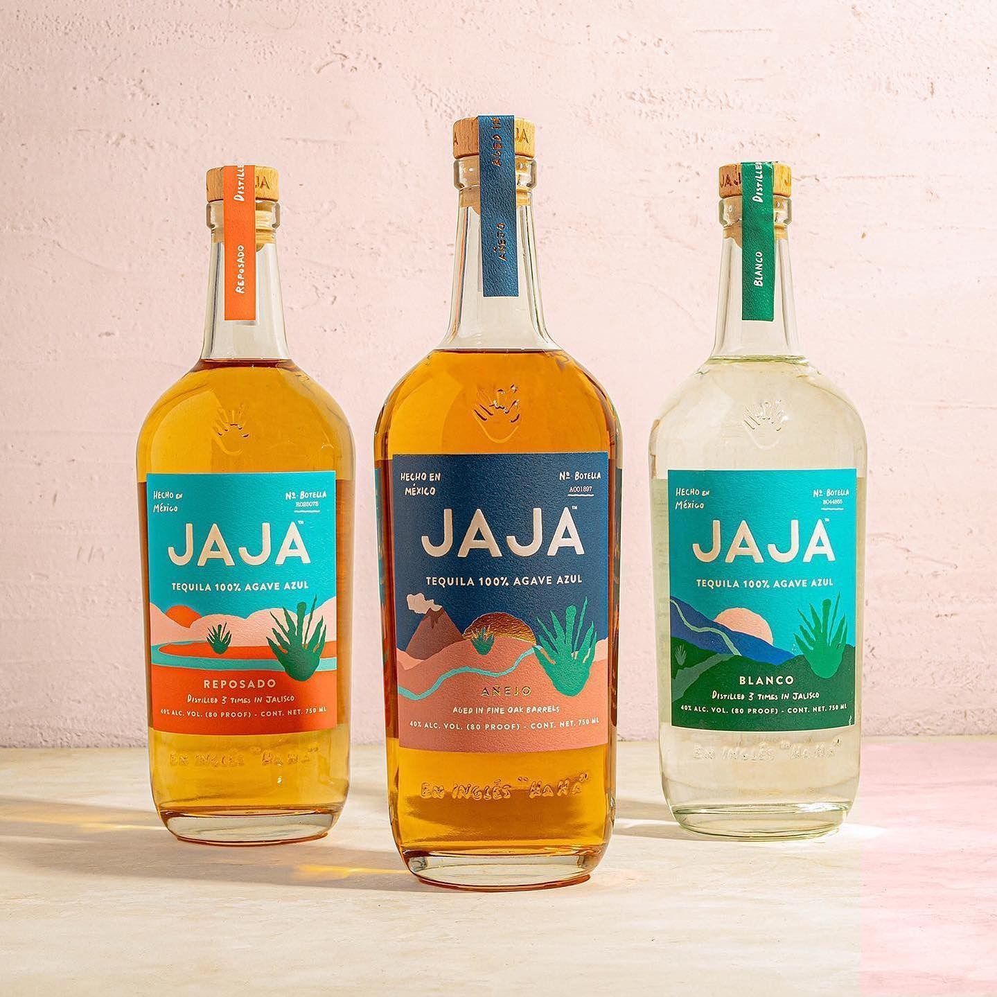 Three bottles of Jaja tequila in different colors, displayed on a table.