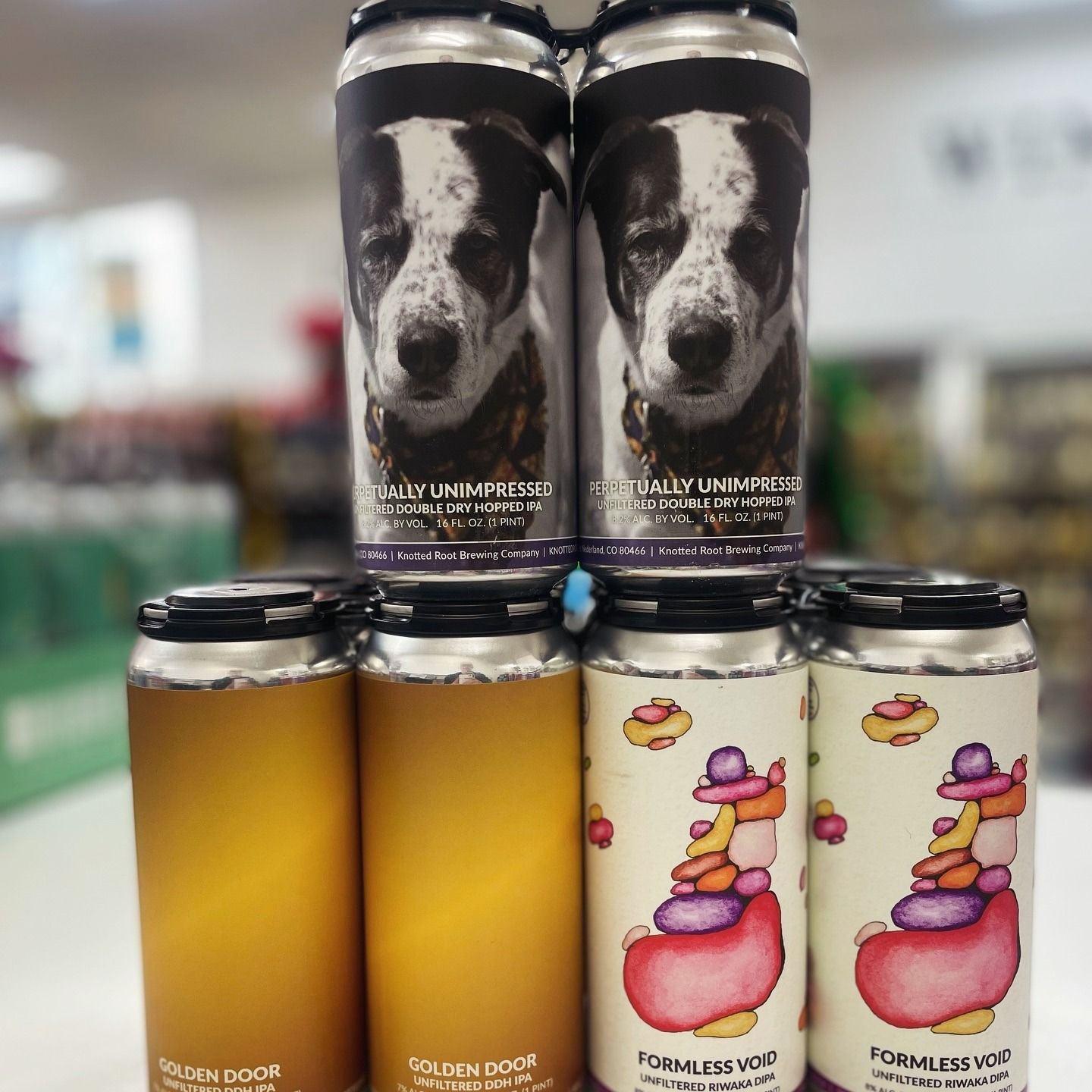 Cans of beer stacked; some with dog portrait, others with colorful cartoon figures. In a store.