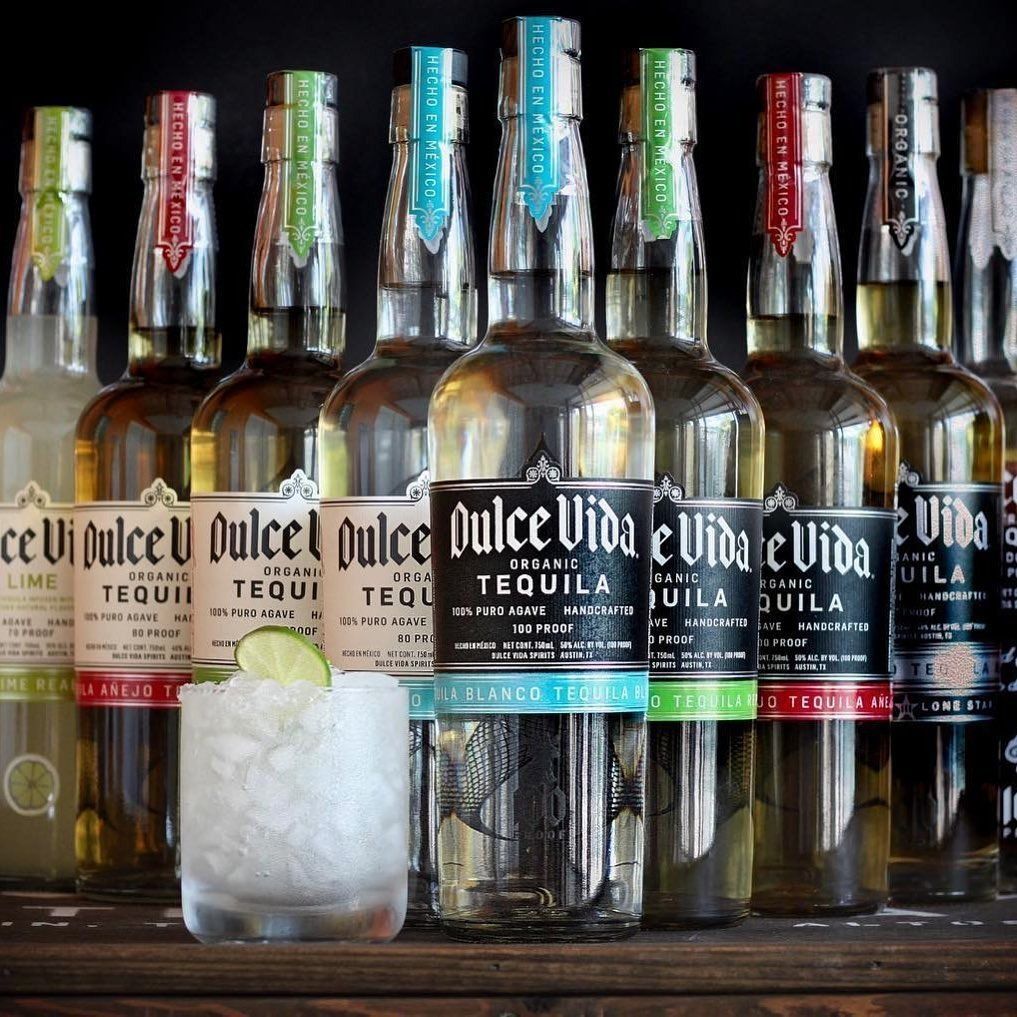 Bottles of Dulce Vida tequila, with a margarita in front.