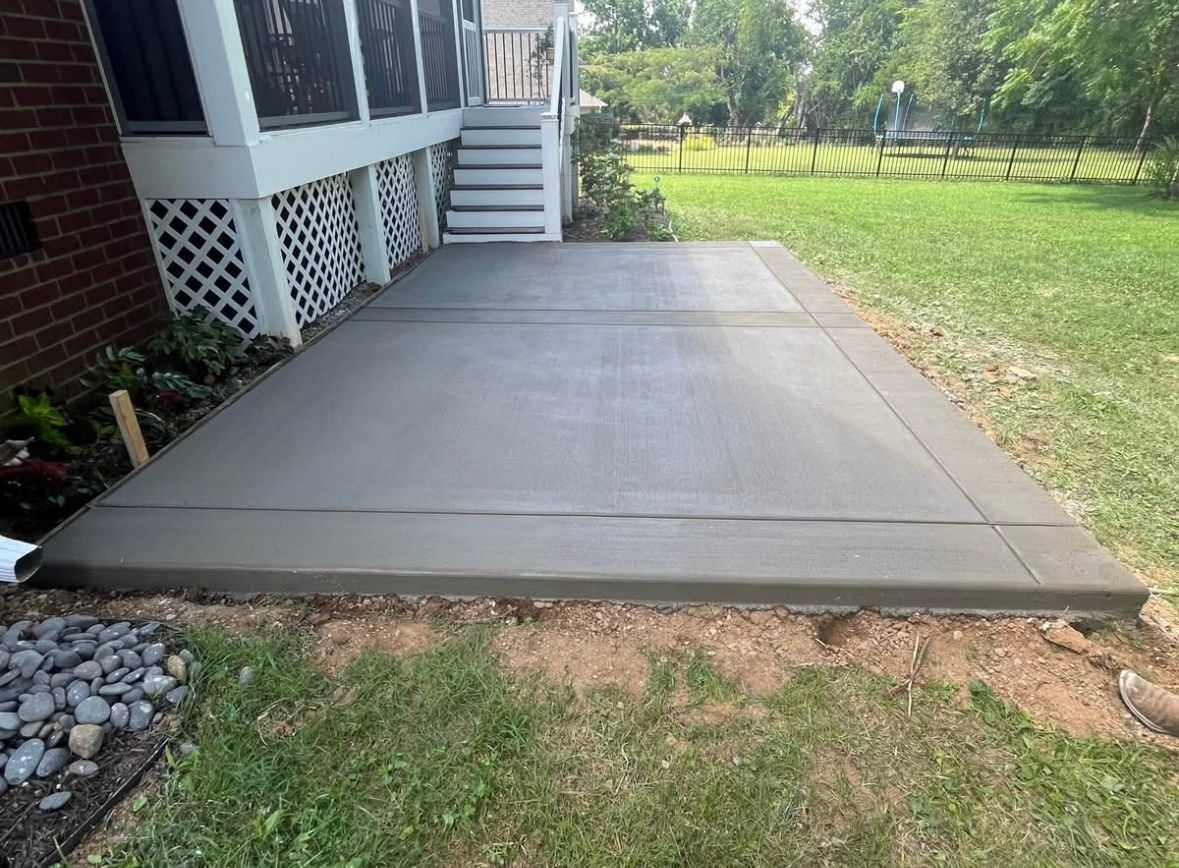 A newly poured concrete patio next to a house and lawn.