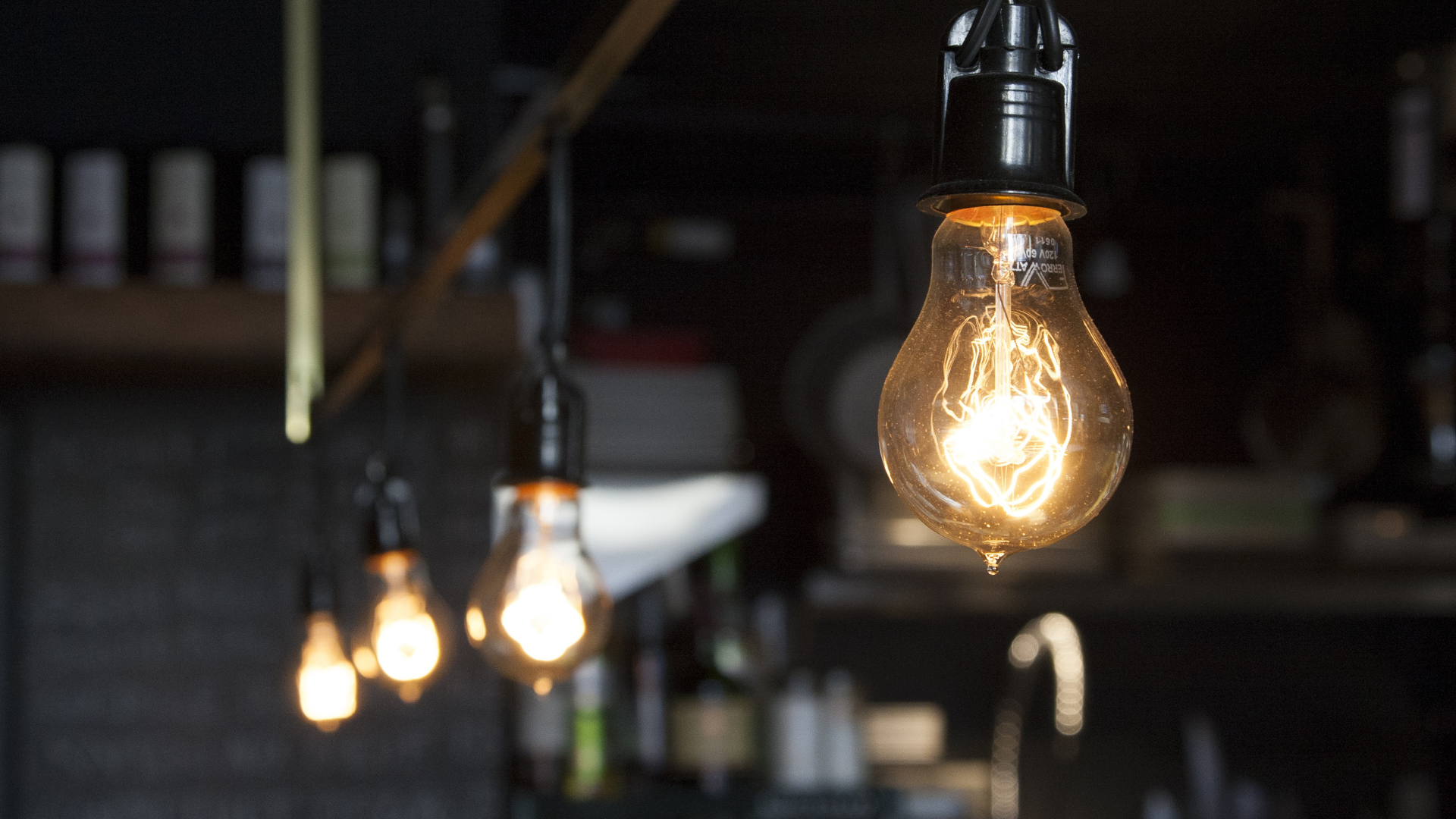 A row of light bulbs hanging from the ceiling in a dark room.