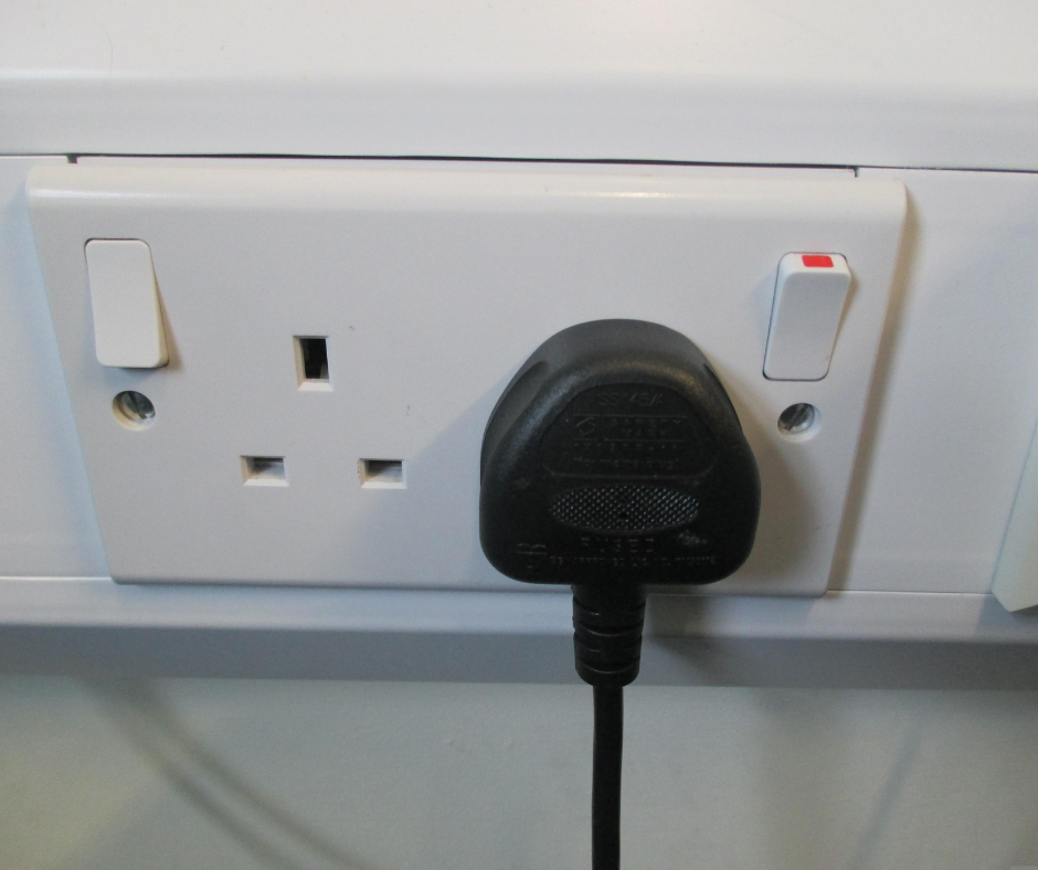 A black plug is plugged into a white electrical outlet
