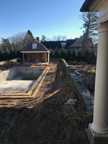 A large swimming pool is being built in the backyard of a house.