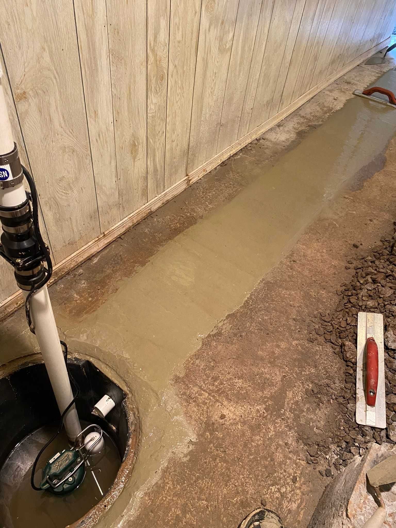 A basement sump pump is being installed in a basement.