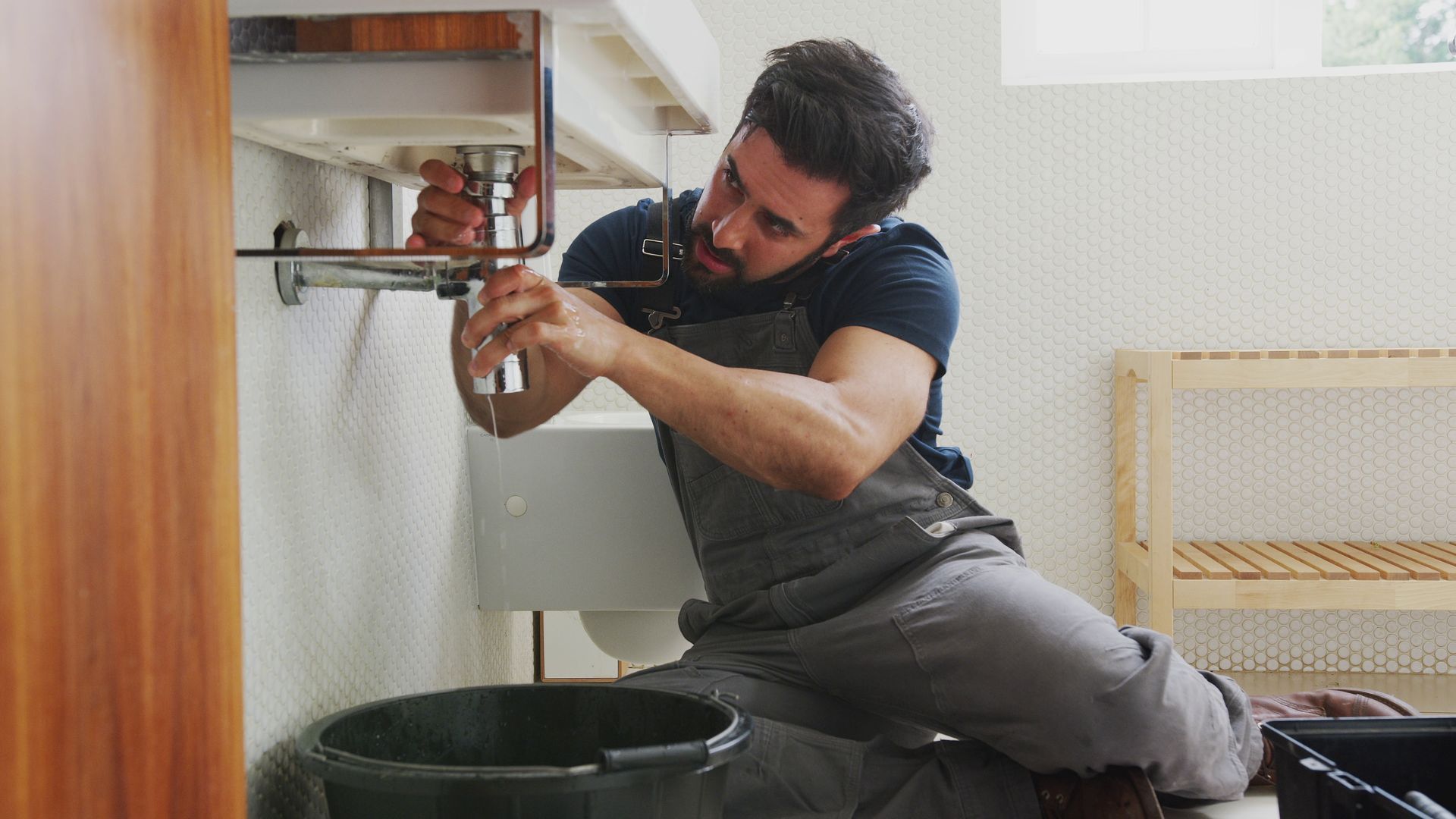 A plumber is fixing a sink in a bathroom.