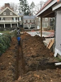 A large pile of dirt is being dug in front of a house.