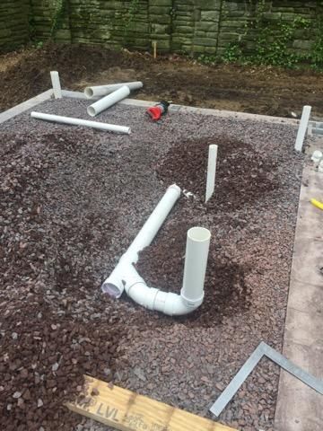 A bunch of pipes are laying on top of a pile of gravel.