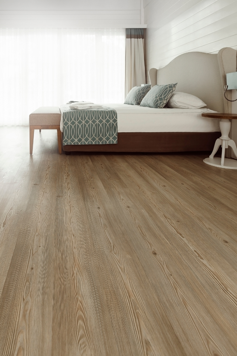 A wooden floor with chairs and a table in the background