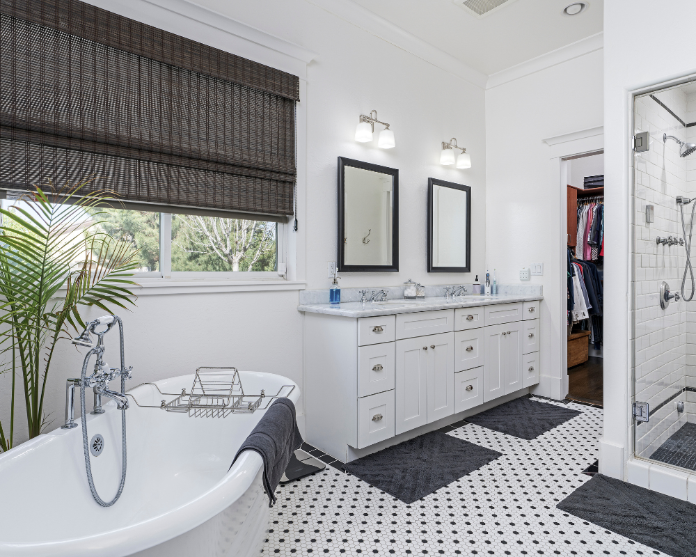 A bathroom with a tub , sinks , mirrors and a walk in closet.