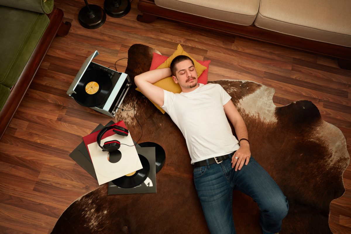 A man is laying on the floor next to a record player.