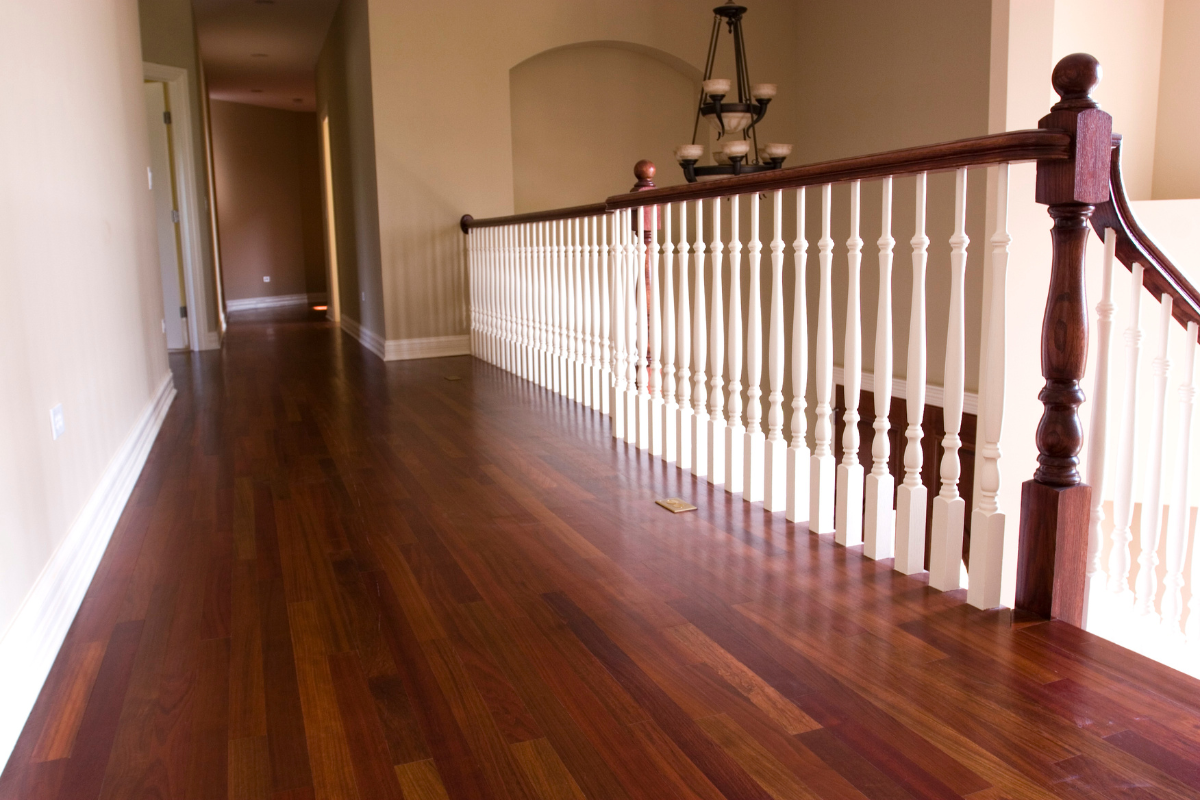 A hallway with hardwood floors and a white railing