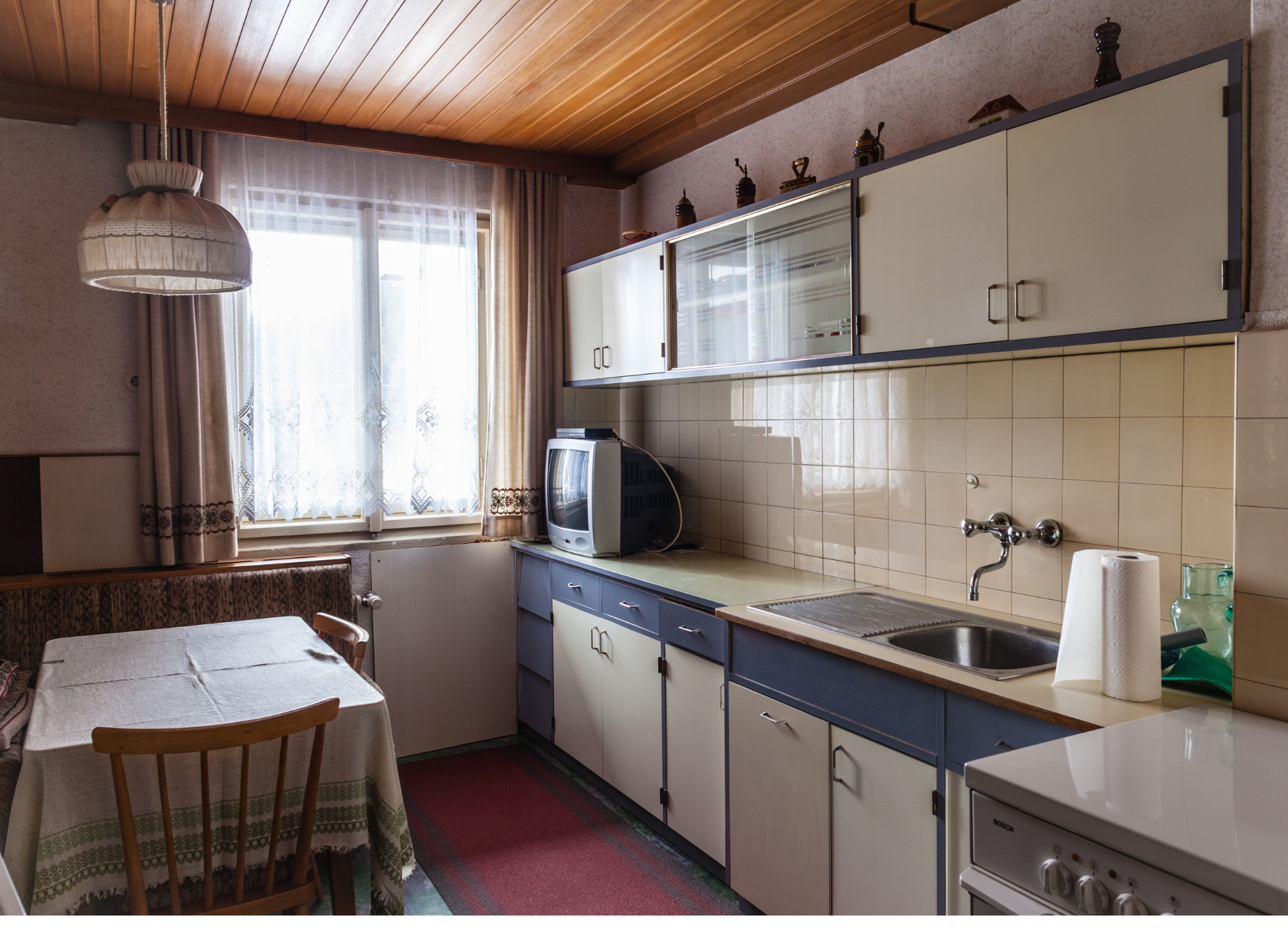 A kitchen with white cabinets , a stove , a microwave , and a sink.