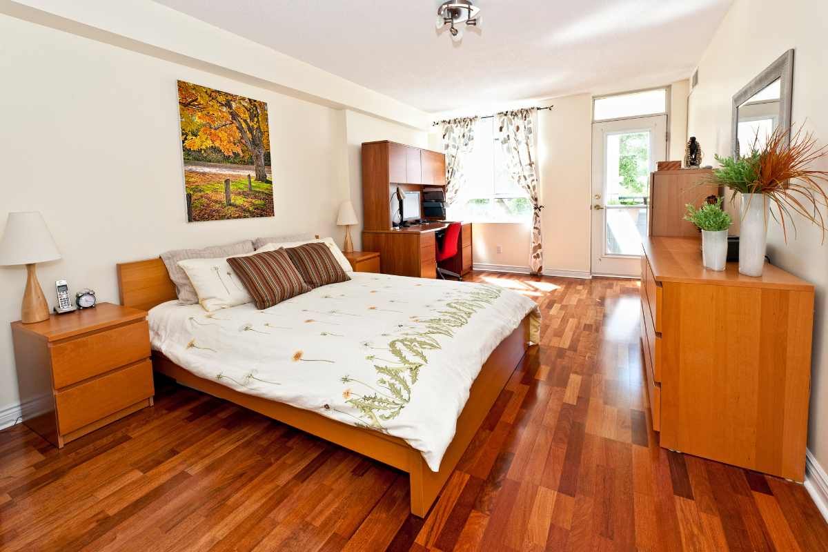 A bedroom with hardwood floors and a large bed