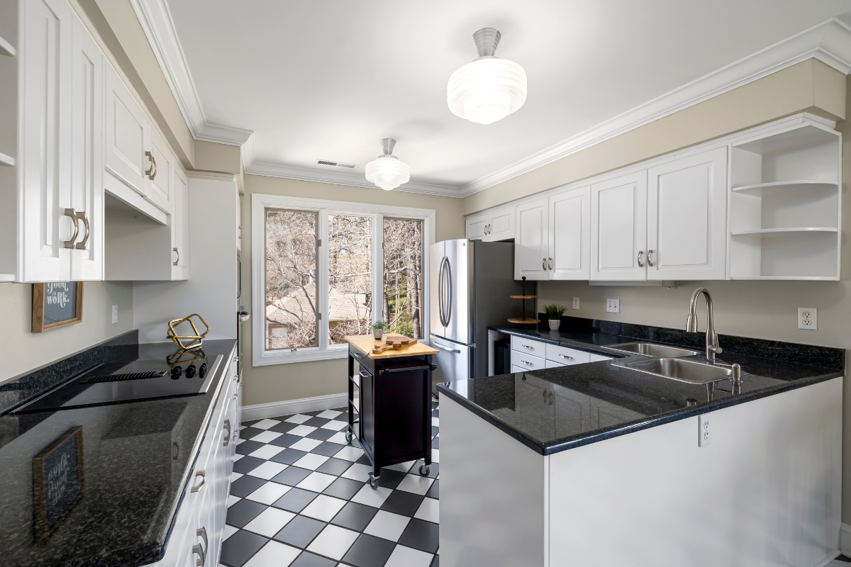 A kitchen with white cabinets , black counter tops , and a checkered floor. Menke Inc. Abilene, TX