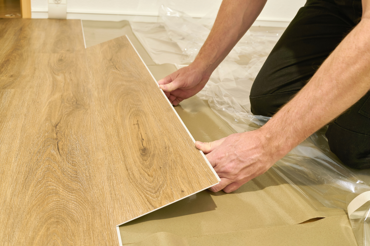 A man is installing a wooden floor in a room.