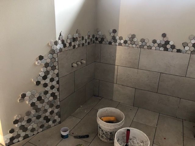 A bathroom with tiles and buckets of paint on the floor