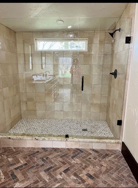 A bathroom with a walk in shower with a glass door.