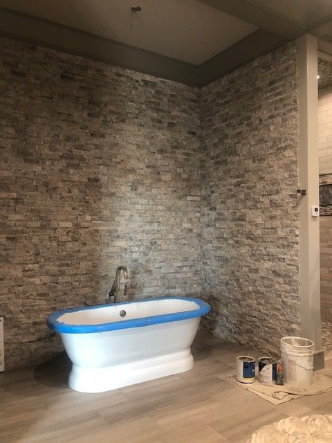 A bathroom with a bathtub and a brick wall.