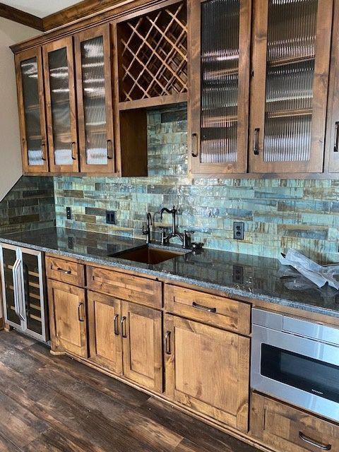 A kitchen with wooden cabinets , granite counter tops , stainless steel appliances and a wine rack. Menke Inc. Abilene, TX