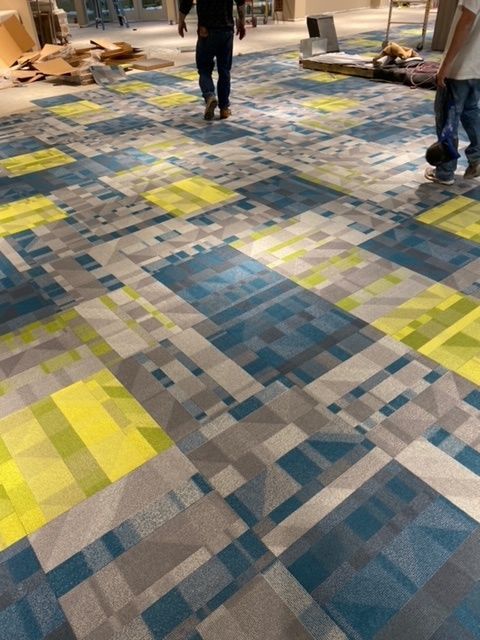 Two men are walking on a colorful carpeted floor