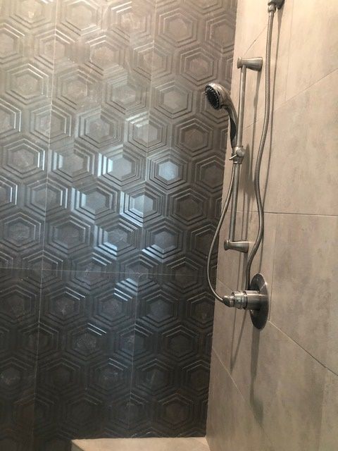 A shower with a geometric pattern on the wall and a shower head.