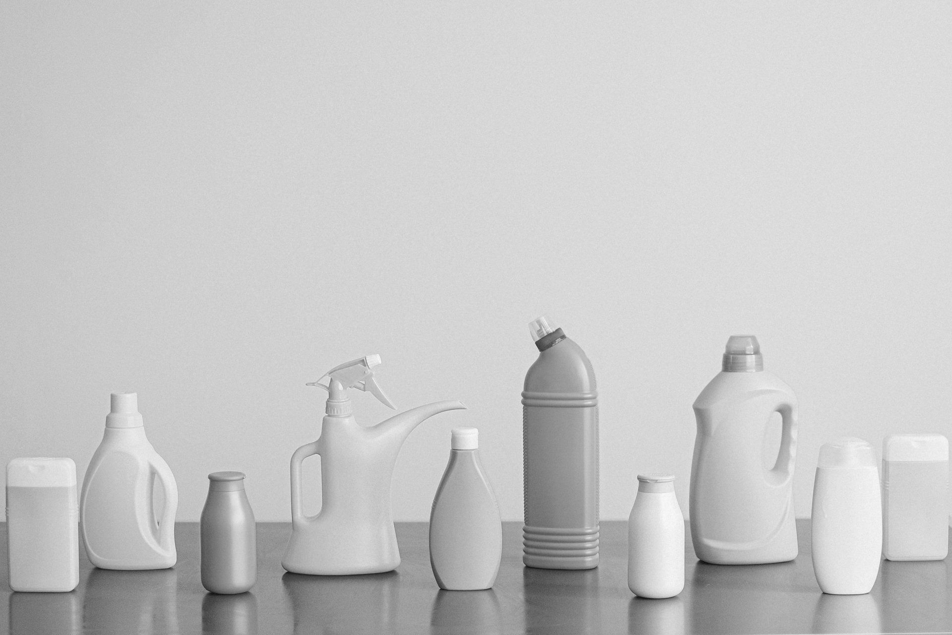 A black and white photo of a row of plastic bottles on a table.