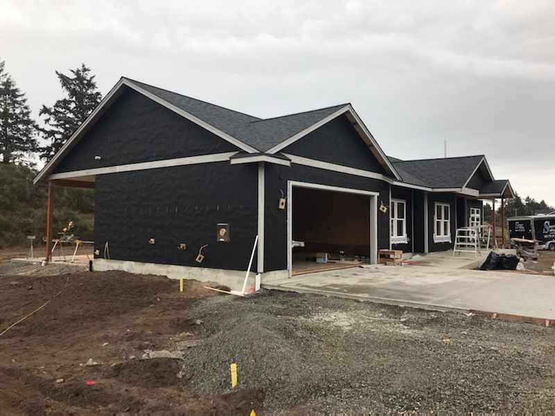 A black house with a garage underneath it