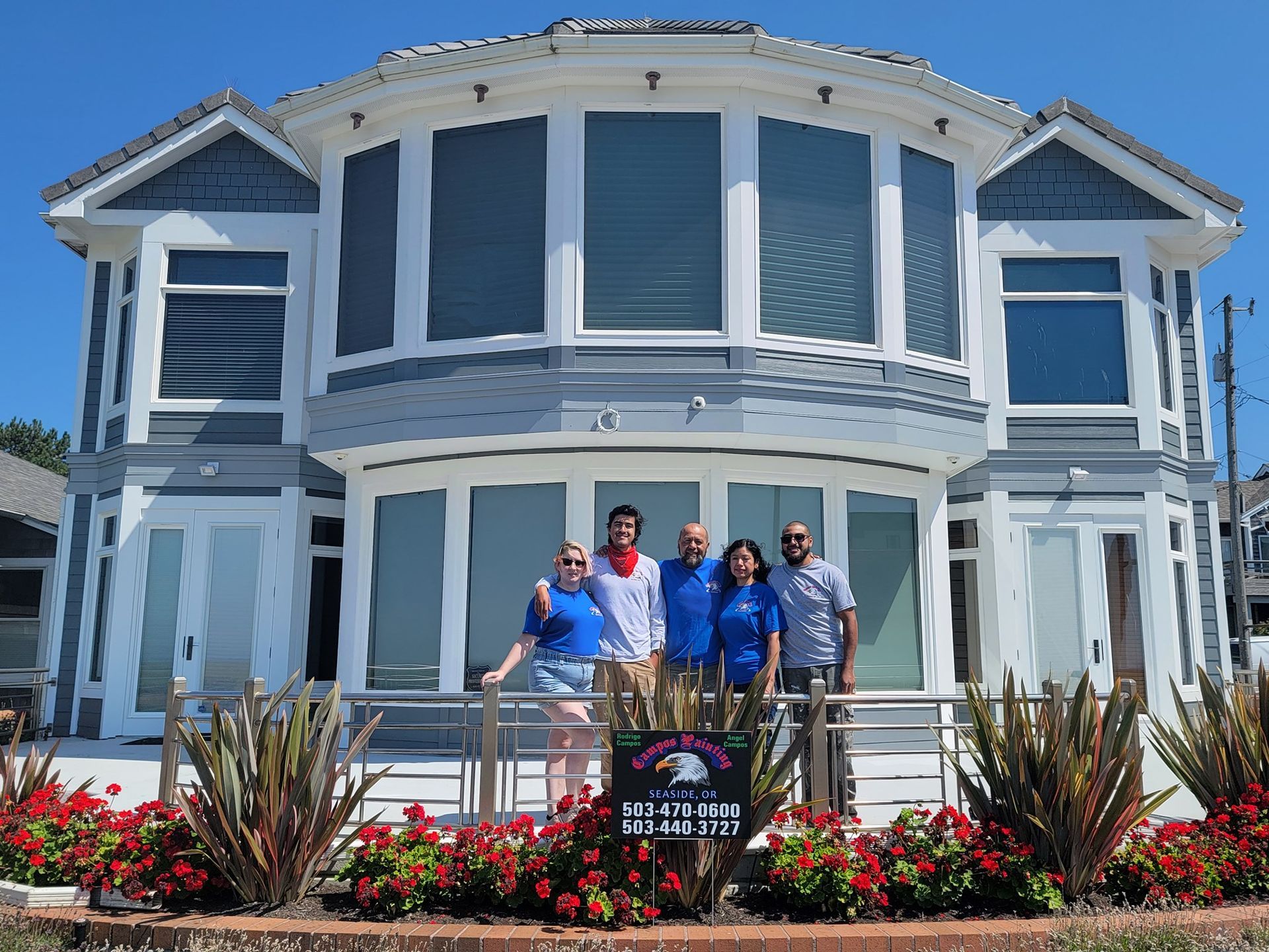 A group of people are standing in front of a large house.