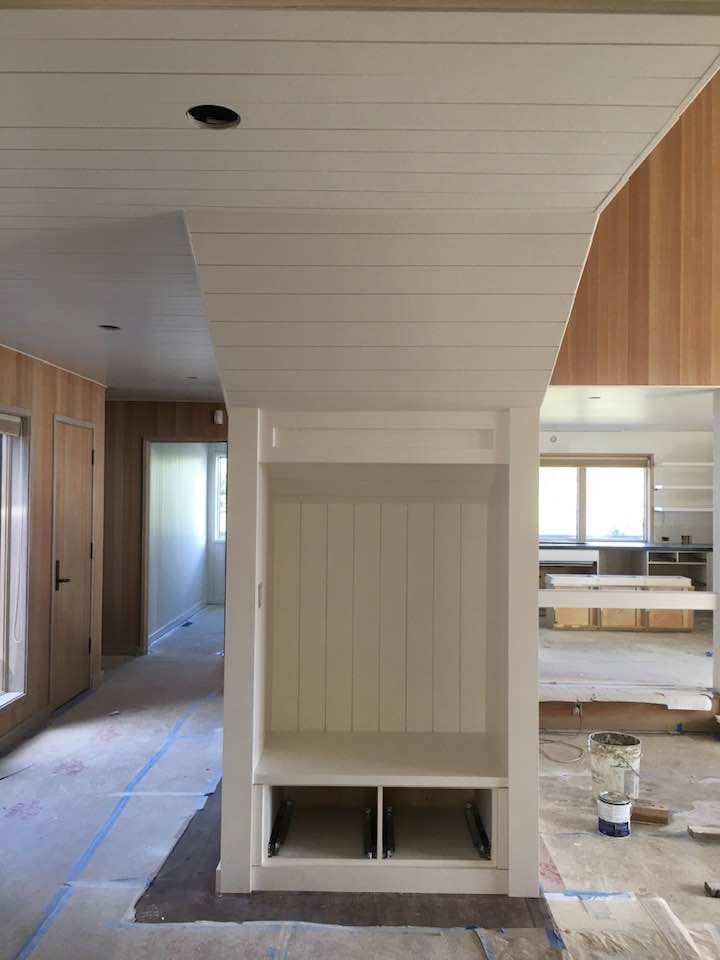 A room with wood paneling and a white shelf in the middle of it.