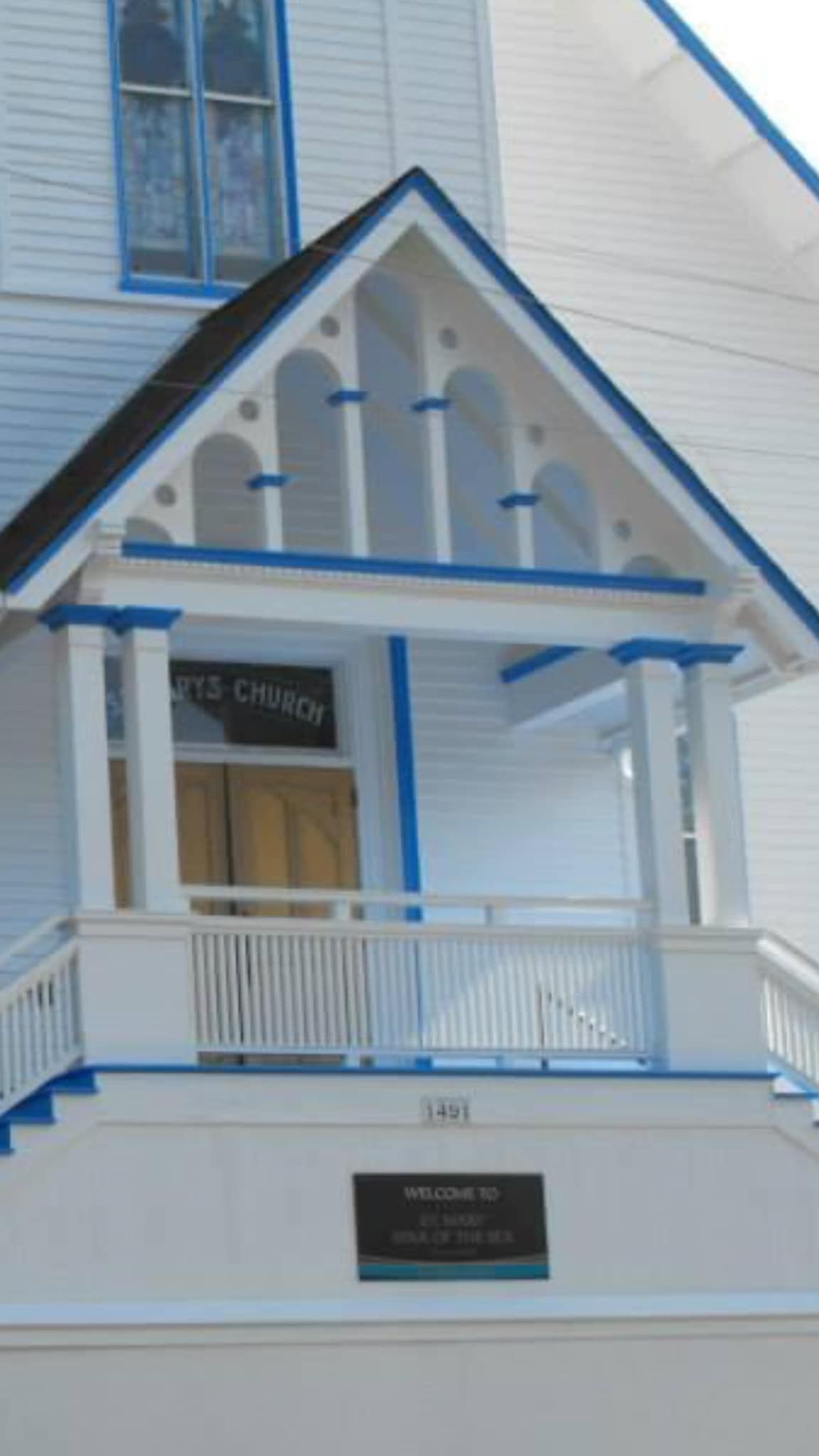 A white house with a blue roof and a porch