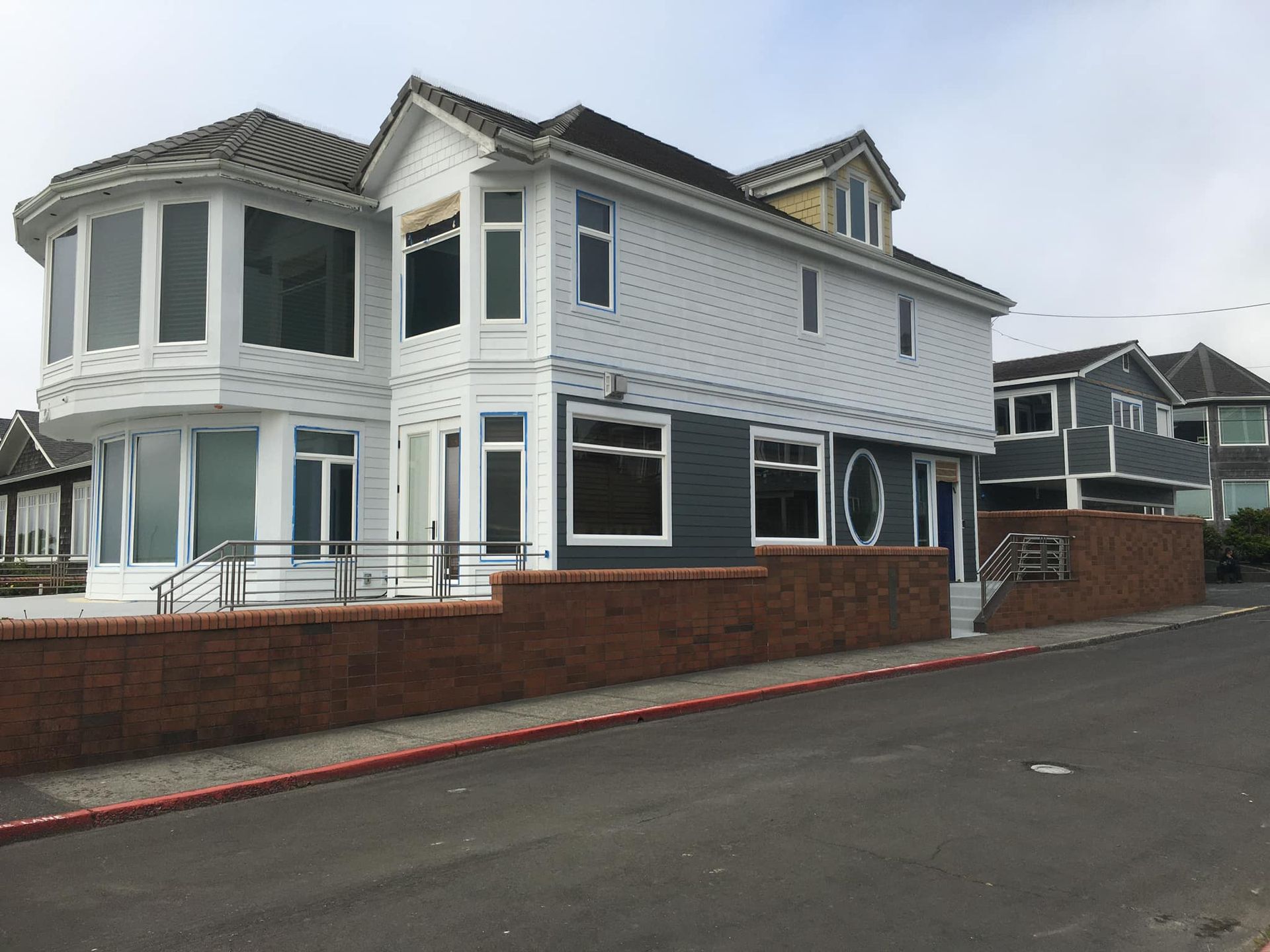 A large white house with a brick wall in front of it