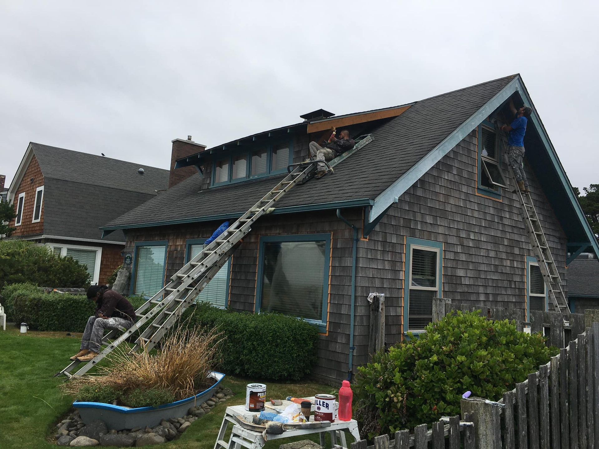 A man on a ladder is working on the roof of a house.