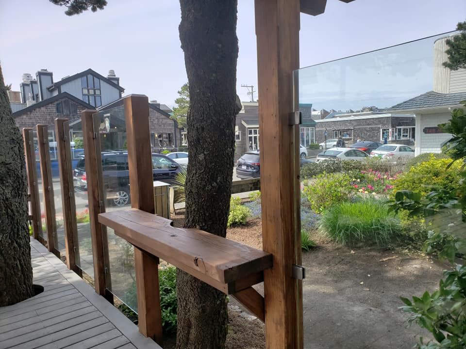 A wooden bench is attached to a tree next to a glass fence.