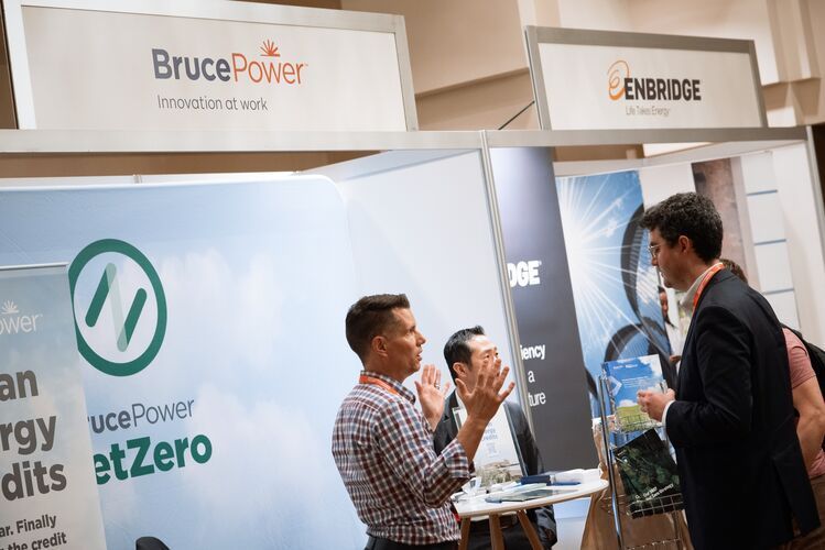 People at booths for Bruce Power and Enbridge, a trade show. One man gestures with hands.