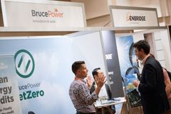 People at booths for Bruce Power and Enbridge, a trade show. One man gestures with hands.