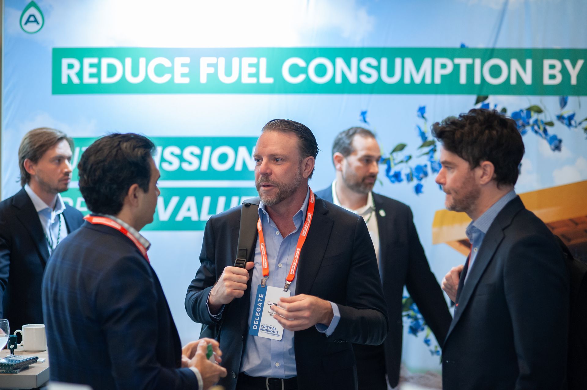 Business professionals conversing at a conference with a banner that states