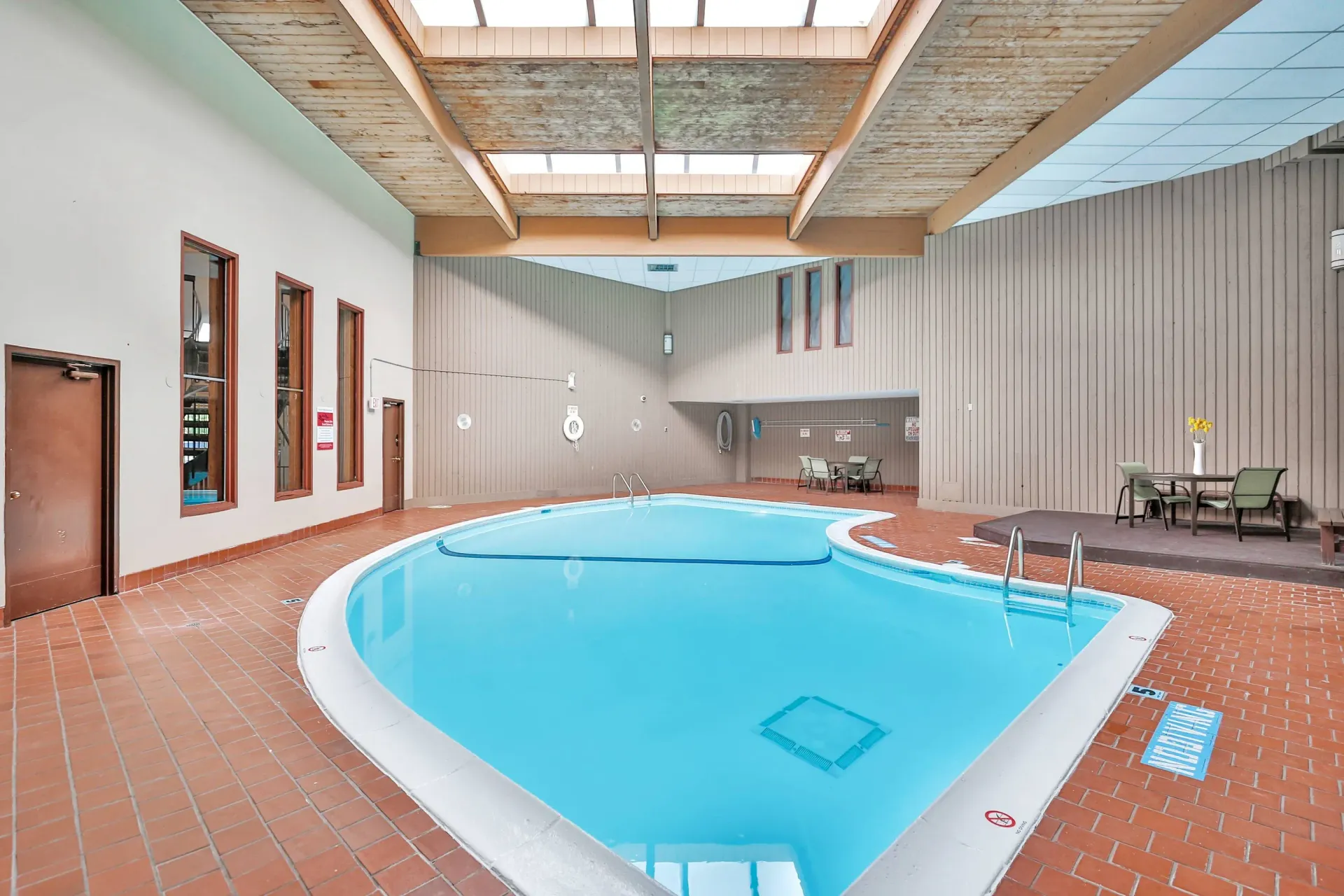 Indoor pool area at a multifamily community with seating and skylight ceiling.